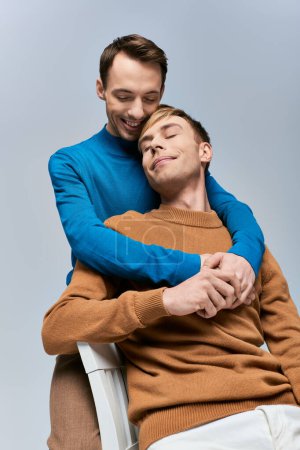 A man sitting in a chair hugging another man in a display of love and affection.