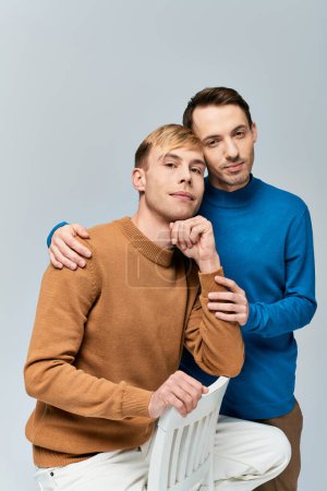 Foto de Una pareja gay amorosa con atuendo casual posando juntos sobre un fondo gris. - Imagen libre de derechos