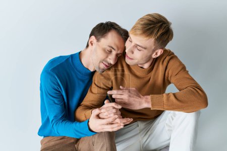 Zwei Männer in Freizeitkleidung sitzen zusammen, in ein Handy vertieft.