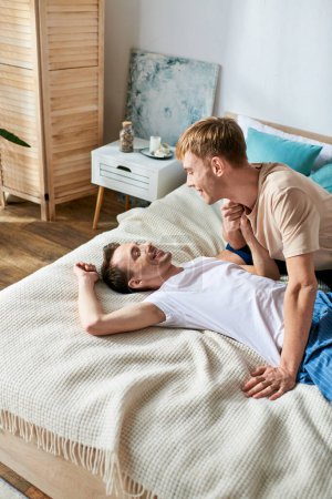 Téléchargez les photos : Deux hommes en tenue décontractée partagent un moment intime sur un lit. - en image libre de droit