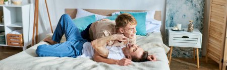 Téléchargez les photos : Deux hommes en tenue décontractée couchés ensemble sur un lit. - en image libre de droit