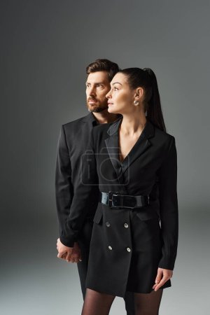 Foto de Un hombre y una mujer en elegante atuendo de pie juntos en un abrazo amoroso. - Imagen libre de derechos