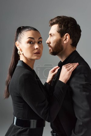 Foto de Un hombre y una mujer en traje elegante se paran uno al lado del otro, exudando amor y estilo. - Imagen libre de derechos