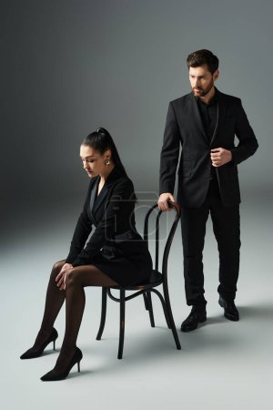 Photo for A man and a woman in elegant attire embrace while sitting on a chair. - Royalty Free Image