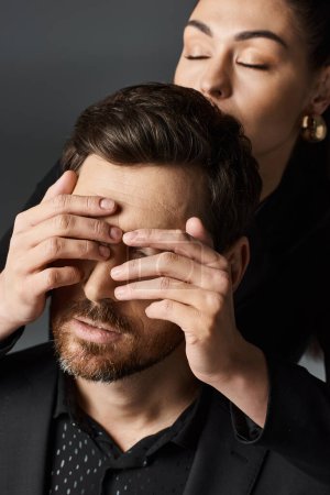 A woman dressed elegantly covers her boyfriend eyes with her hands.