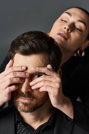 Mujer en traje elegante cubriendo los ojos de su novio con las manos.