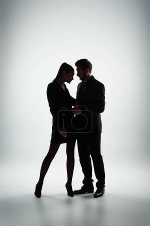 Foto de Un hombre y una mujer en elegante atuendo se unen contra un fondo blanco. - Imagen libre de derechos