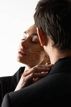 Frau berührt Mann in eleganter Kleidung am Kragen.