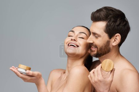 Foto de Atractiva pareja posando con tarro de crema, aplicando cuidado de la piel. - Imagen libre de derechos
