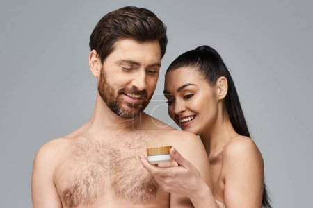 Foto de Hombre y mujer aplicando cuidado de la piel, el hombre tiene tarro de crema. - Imagen libre de derechos