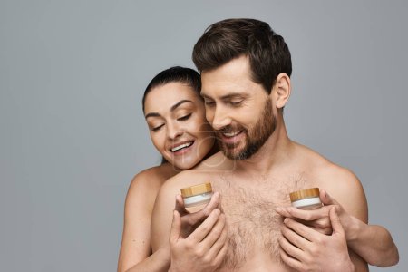 Téléchargez les photos : Un homme et une femme tenant un pot de crème, appliquant des soins de la peau. - en image libre de droit