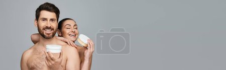 Foto de Pareja feliz elegantemente sostiene un frasco de crema, mostrando su rutina de cuidado de la piel. - Imagen libre de derechos
