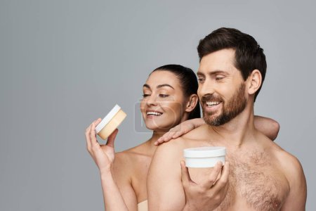 Foto de Jolly pareja elegantemente sostienen un frasco de crema, mostrando su rutina de cuidado de la piel. - Imagen libre de derechos