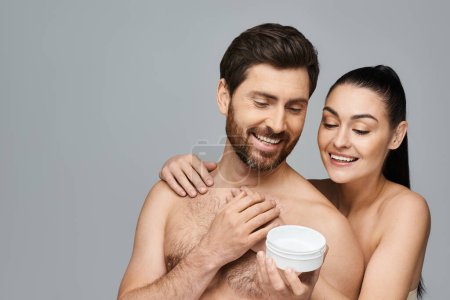 Téléchargez les photos : Couple joyeux tenir élégamment un pot de crème, mettant en valeur leur routine de soins de la peau. - en image libre de droit