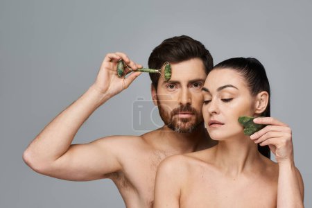 Attractive couple, radiating beauty, using face roller and gua sha together.