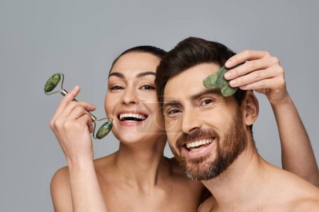 Photo for Jolly couple, radiating beauty, using face roller and gua sha together. - Royalty Free Image