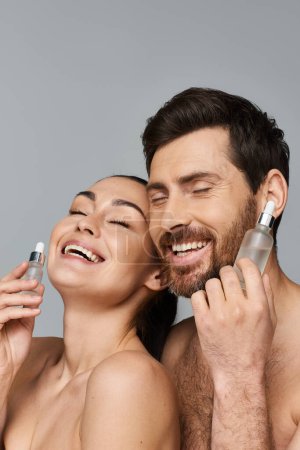 Alluring man and woman using serum as skin care.