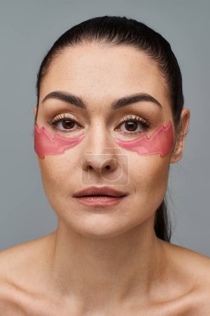 Woman with pink patches applied to her face, posing for a skincare treatment.