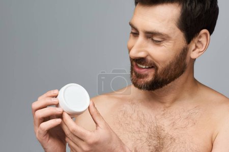 Téléchargez les photos : Homme torse nu tenant un récipient de crème blanche. - en image libre de droit