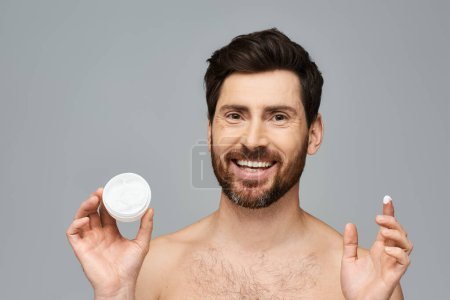 Hombre sin camisa aplicando crema, mostrando rutina de cuidado de la piel.