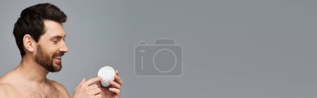 Foto de El hombre sin camisa sostiene un frasco de crema. - Imagen libre de derechos