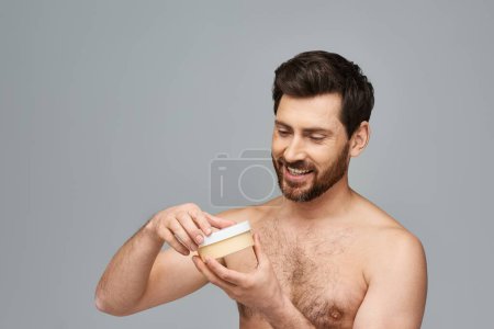 Téléchargez les photos : L'homme barbu tient un pot de crème. - en image libre de droit
