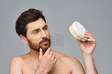 Hombre sin camisa con contenedor de crema, régimen de cuidado de la piel.