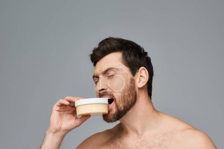 Photo for Bearded man biting a jar of cream. - Royalty Free Image