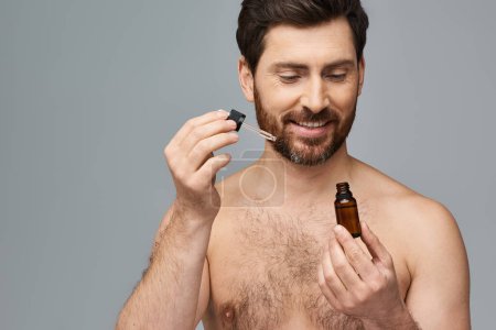 Foto de Un hombre sin camisa que se aplica suero en la cara. - Imagen libre de derechos