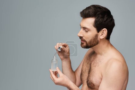 Photo for A shirtless man holds a bottle of serum. - Royalty Free Image