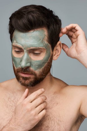 Téléchargez les photos : Un homme appliquant un masque facial pour les soins de la peau. - en image libre de droit