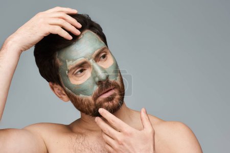 Téléchargez les photos : Beau homme appliquant un masque facial. - en image libre de droit