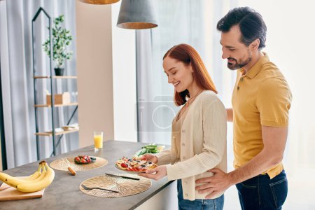 Eine rothaarige Frau und ein bärtiger Mann bereiten in einer modernen Küche fröhlich gemeinsam Essen zu und verbinden sich über die Kunst des Kochens.