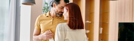 Téléchargez les photos : Une femme rousse et un homme barbu embrassant dans leur salon élégant, partageant un moment d'intimité et de connexion. - en image libre de droit