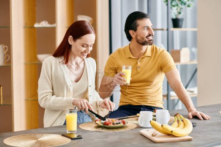 Eine rothaarige Frau und ein bärtiger Mann frühstücken gemütlich zusammen in ihrer modernen Küche.