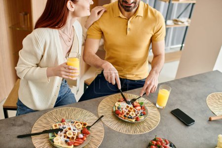 Téléchargez les photos : Couple dégustant une salade saine ensemble dans leur cuisine moderne. - en image libre de droit