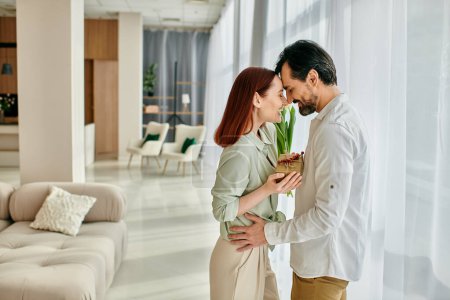 Un jeune homme et une jeune femme, une femme rousse et un homme barbu, se tiennent ensemble dans le salon d'un appartement moderne, passant du temps ensemble de qualité.