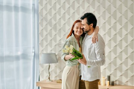Photo for A beautiful adult couple, a redhead woman, and a bearded man sharing an intimate moment, hugging in their modern living room. - Royalty Free Image