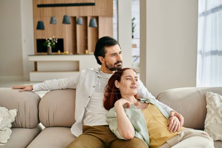 Photo for A redhead woman and bearded man enjoying each others company on a comfortable couch in a stylish living room. - Royalty Free Image