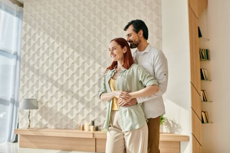 Femme rousse et homme barbu se tiennent ensemble dans un salon moderne, passer du temps de qualité dans un cadre confortable.