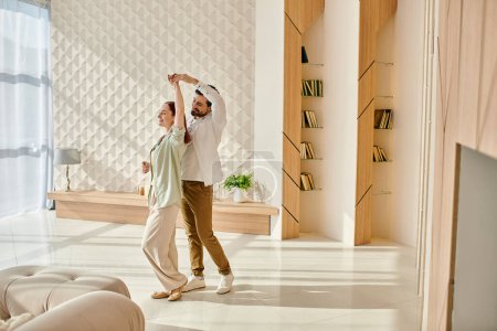A beautiful adult couple - a redhead woman and bearded man gracefully dancing in their modern apartments living room.