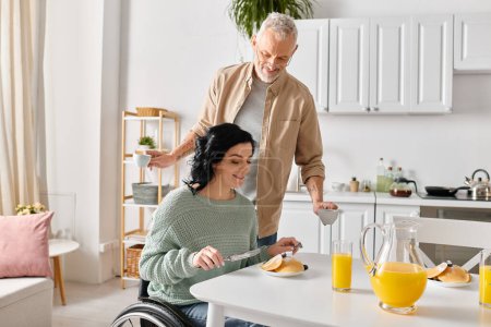 Une femme handicapée en fauteuil roulant et son mari cuisinent ensemble dans leur cuisine à la maison.