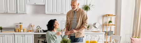 Photo for A disabled woman in a wheelchair and her husband sharing a moment in their kitchen at home. - Royalty Free Image