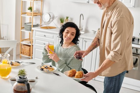 Eine behinderte Frau im Rollstuhl und ihr Mann zusammen in ihrer Küche zu Hause, umgeben von Liebe und Wärme.