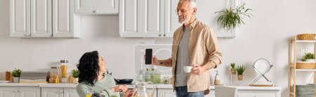 Photo for A man and a woman, the latter in a wheelchair, stand together in a cozy kitchen at home. - Royalty Free Image