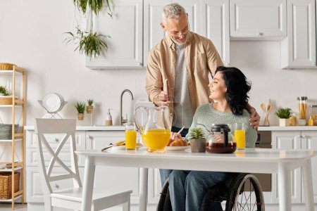 Un homme se tient à côté de sa femme dans un fauteuil roulant dans leur cuisine maison.