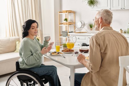 Ein Mann und eine Frau im Rollstuhl teilen sich einen Moment an einem Küchentisch in ihrem Haus und umarmen sich, um ihre Liebe und Einheit auszudrücken.