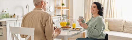 Une femme handicapée en fauteuil roulant et son mari s'assoient ensemble à la table de la cuisine, partageant un moment de calme.