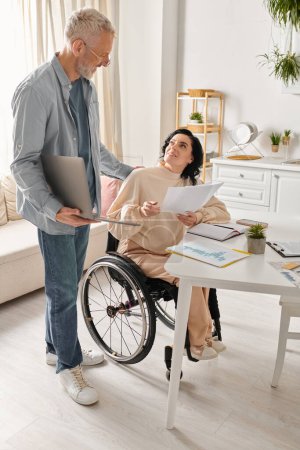 Une femme handicapée en fauteuil roulant et son mari en fauteuil roulant travaillent joyeusement ensemble dans leur cuisine à la maison.