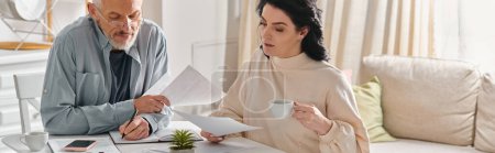 Photo for A man and woman sit at a table, surrounded by papers, engaged in a serious discussion. - Royalty Free Image